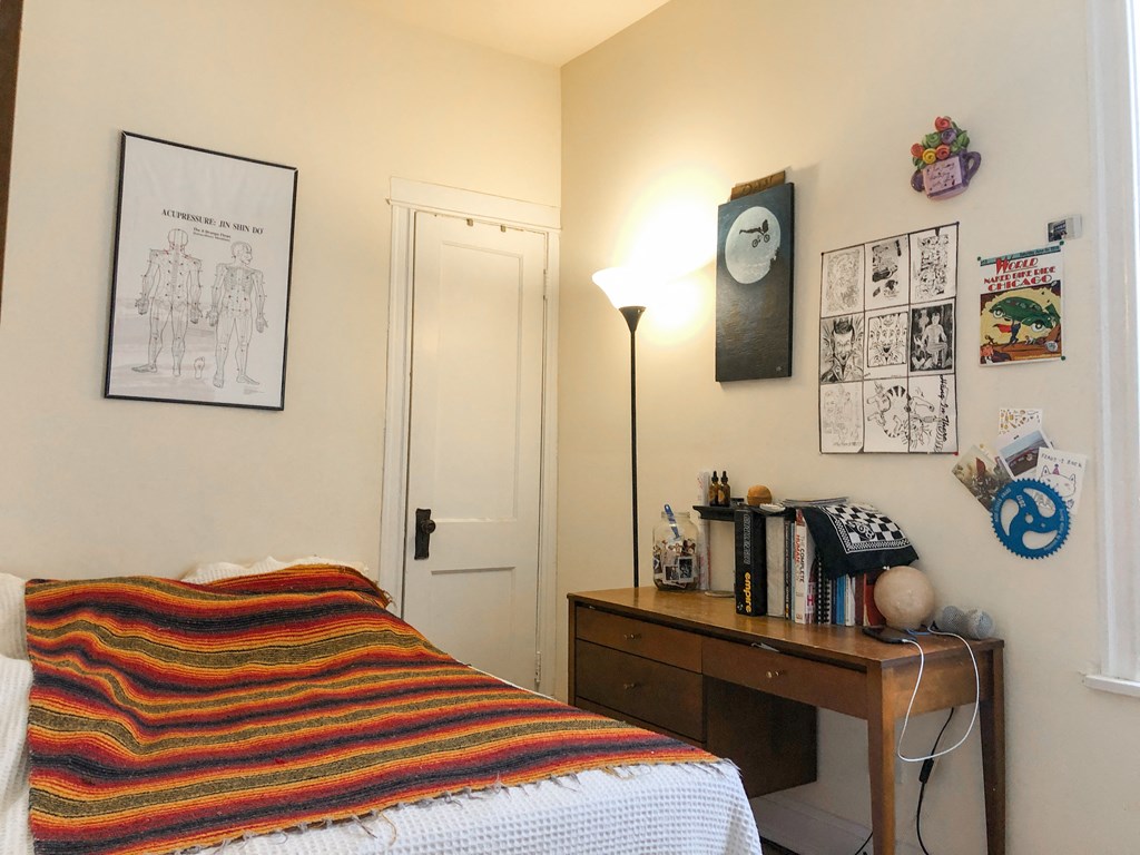 a bedroom with a bed and a desk with a lamp