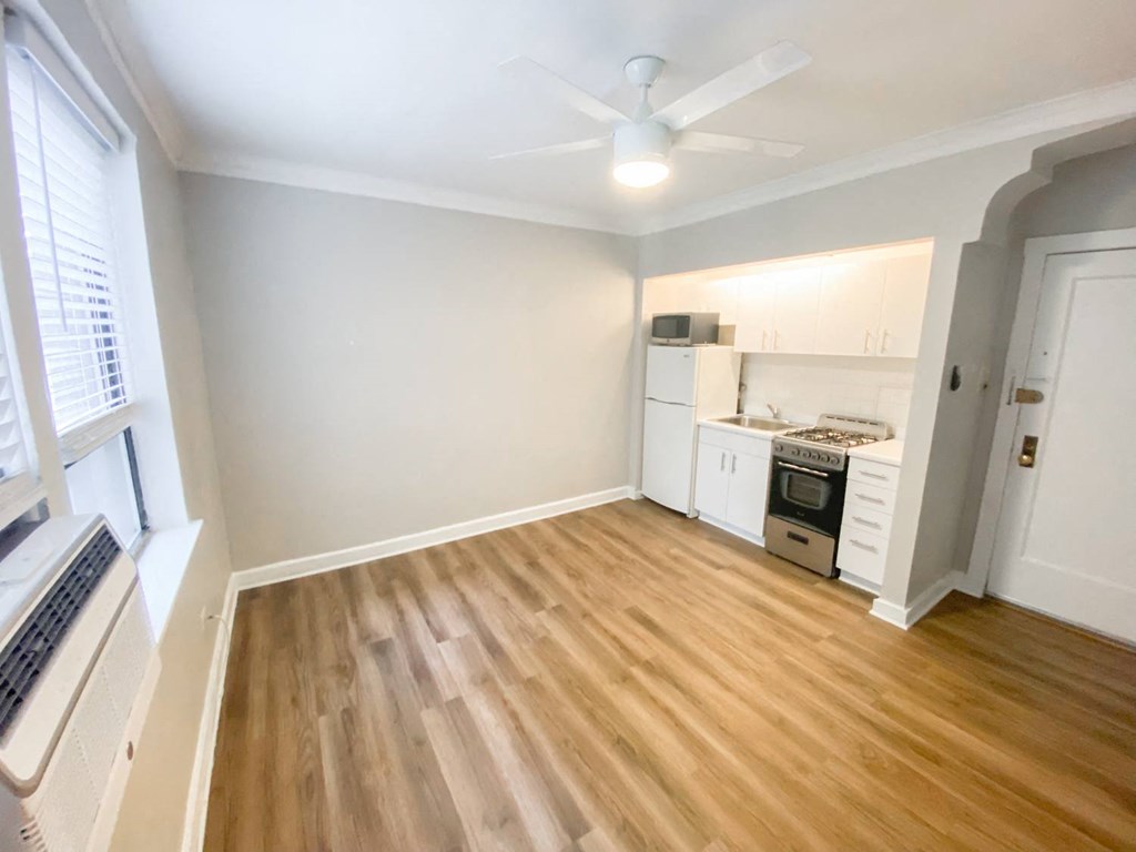 a living room and kitchen with wood flooring and a ceiling fan