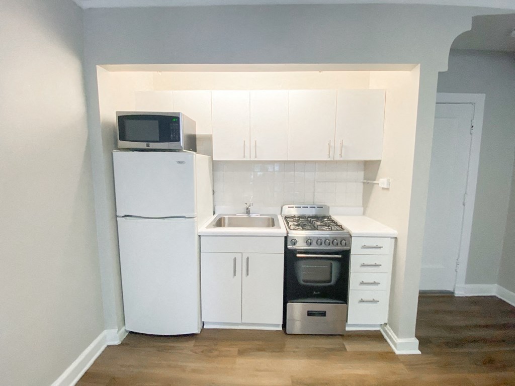 an empty kitchen with white cabinets and appliances and a white refrigerator