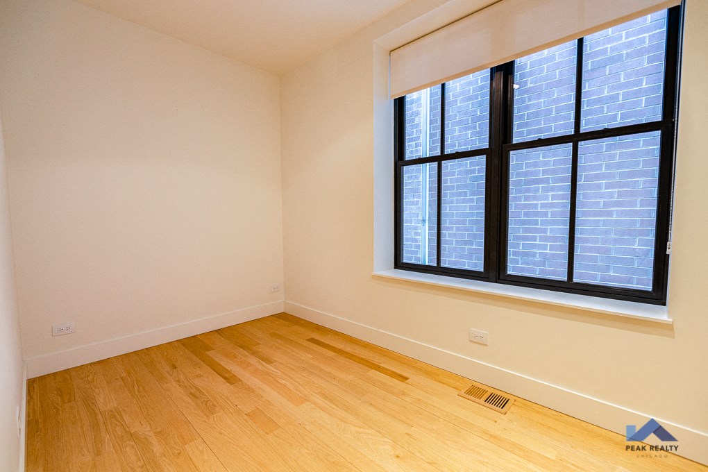 an empty room with a large window and wooden floors