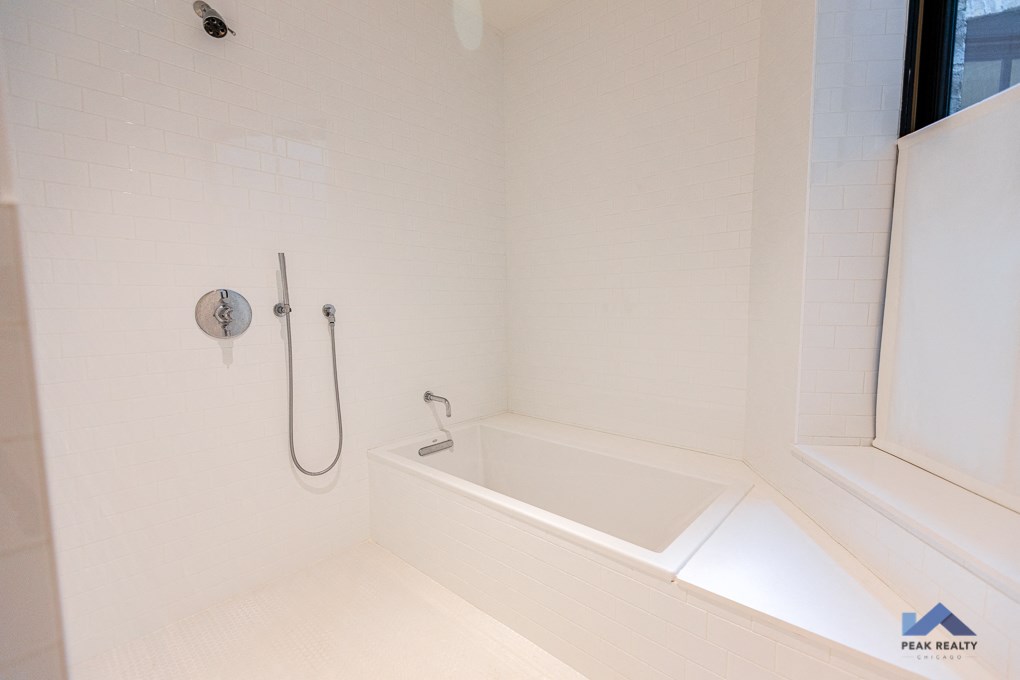 a white bathroom with a tub and shower and a window