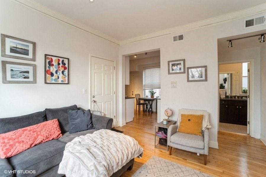 a living room with a couch and a chair and a door to a kitchen