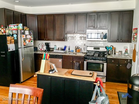 A kitchen with a black fridge and brown cabinets.