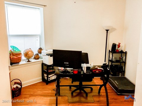 A room with a desk, chair, and computer monitor.