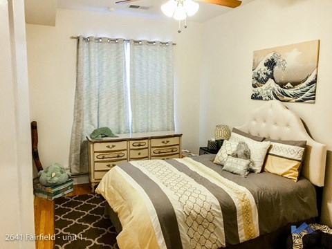 A bedroom with a bed, dresser, and ceiling fan.
