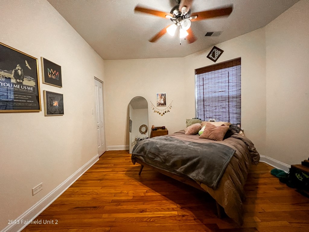 a bedroom with a bed and a ceiling fan and a mirror