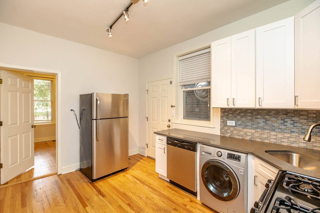 a kitchen with a washer and dryer and a stainless steel refrigerator
