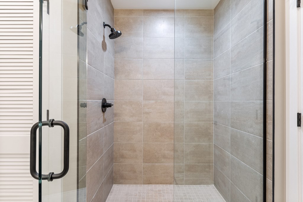 a large tiled shower in a bathroom with a glass door