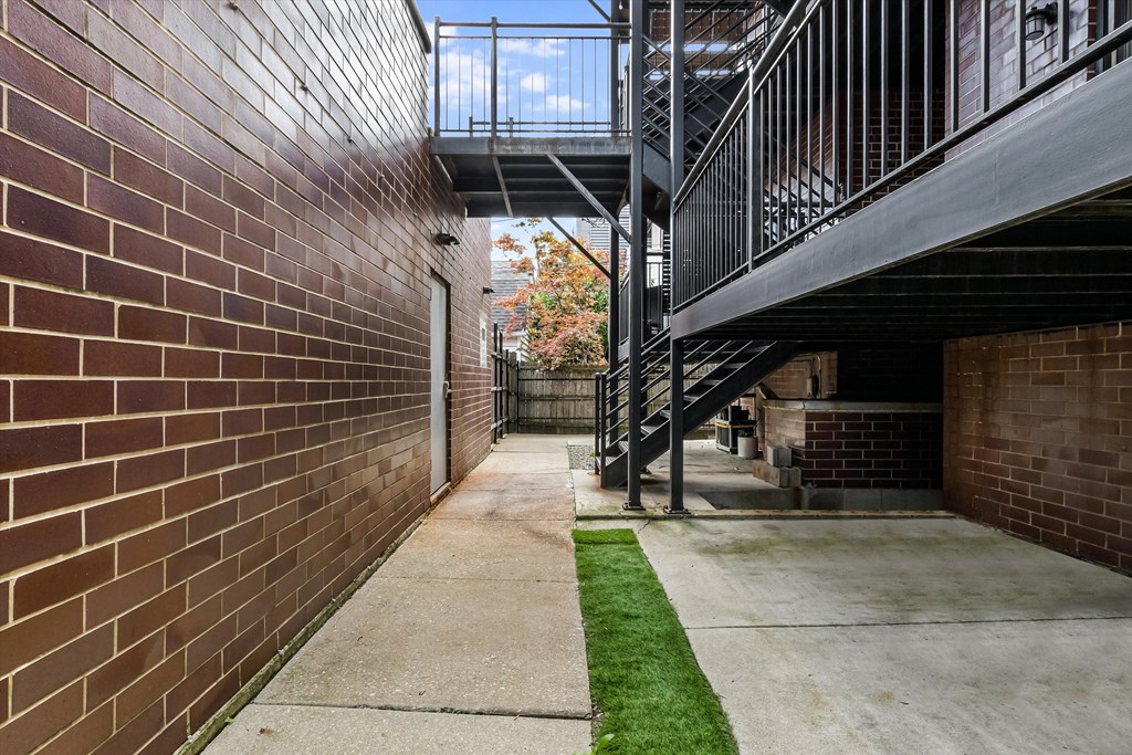 A long, narrow walkway with a metal railing on one side and a brick wall on the other.