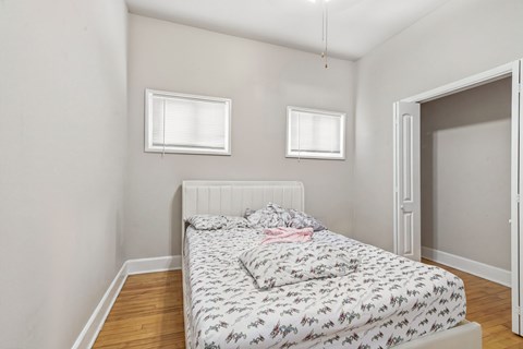 A bedroom with a bed and two windows.