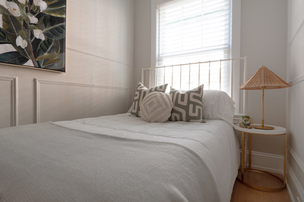 a small bedroom with a bed with pillows and a lamp