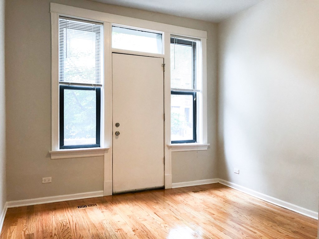 an empty room with a door and two windows