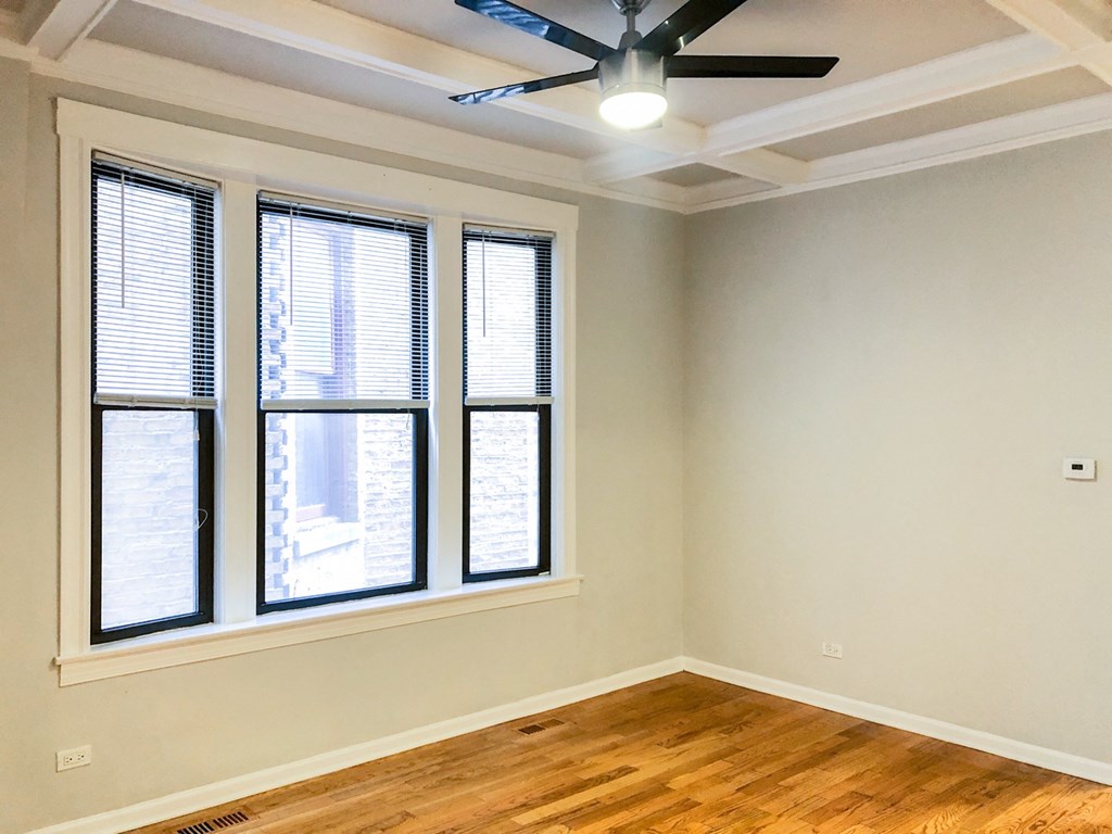 an empty room with three windows and a ceiling fan