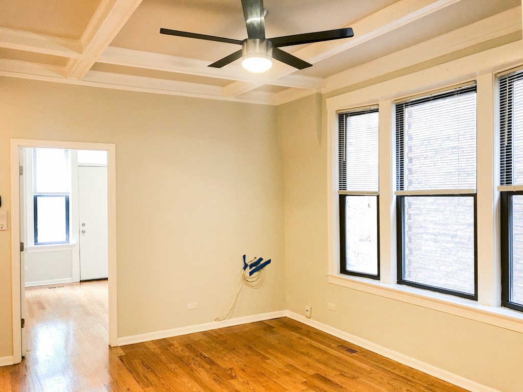 an empty living room with a ceiling fan and windows
