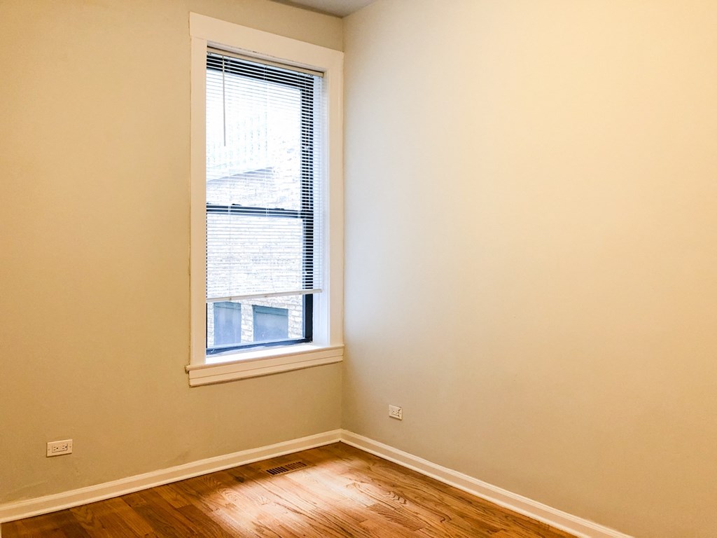 an empty room with a window and wooden floors