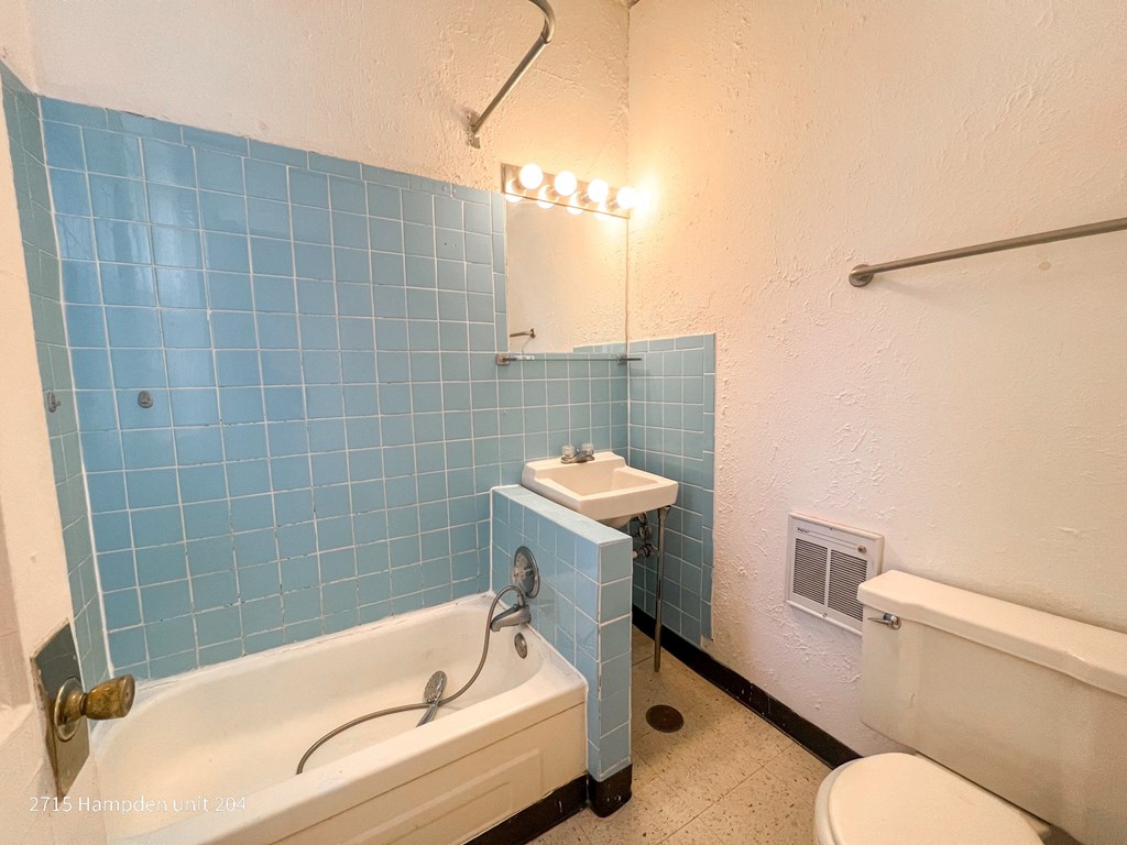 A bathroom with blue tiles and a white tub.