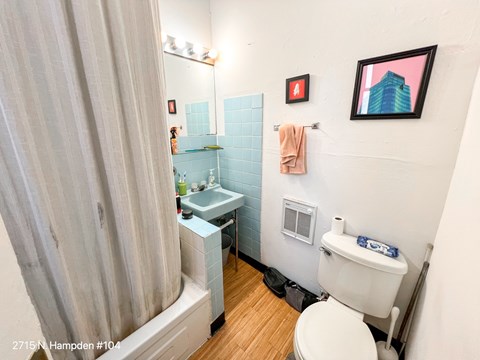 A small bathroom with a toilet, sink, and shower.