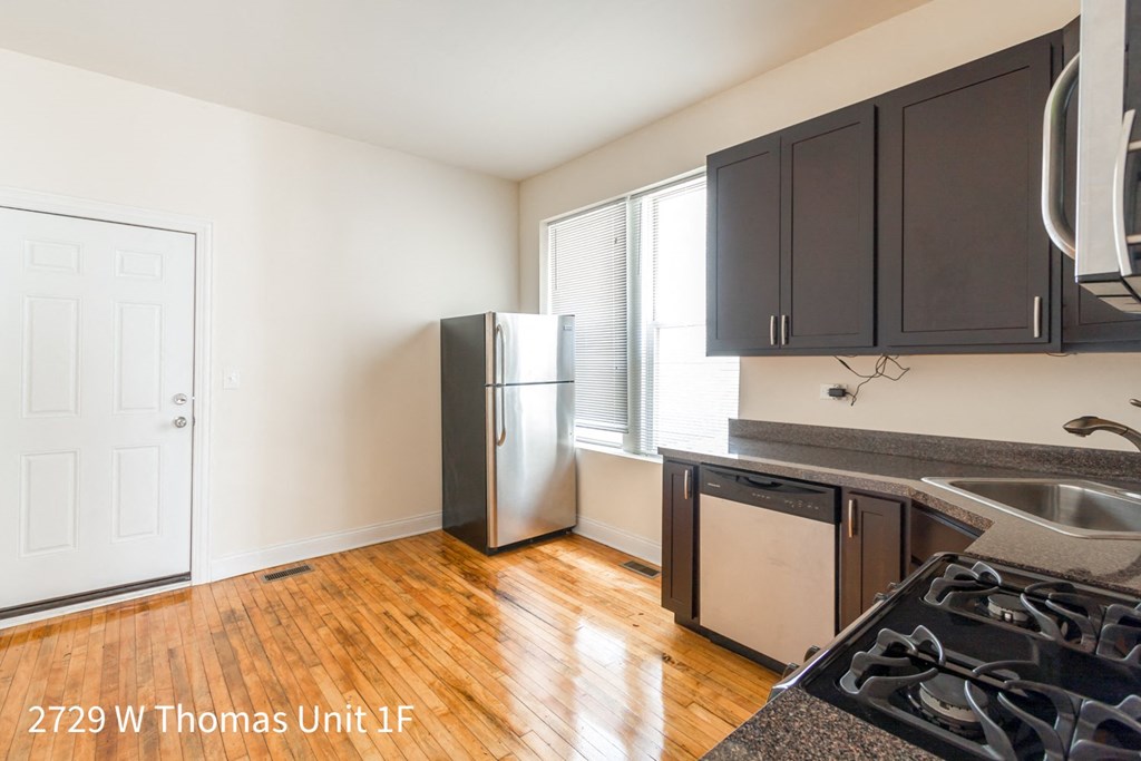 a kitchen with black cabinets and a stainless steel refrigerator
