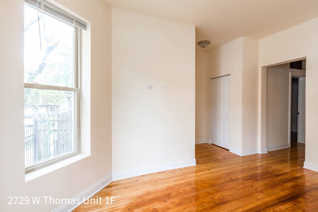 a living room with a wood floor and a large window