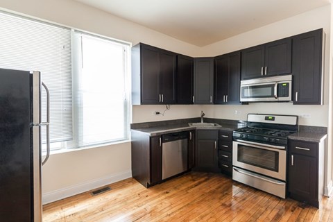 A kitchen with black cabinets and stainless steel appliances.