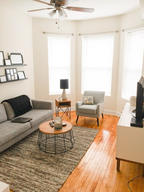 A living room with a grey couch, a small table with a candle, and a television.
