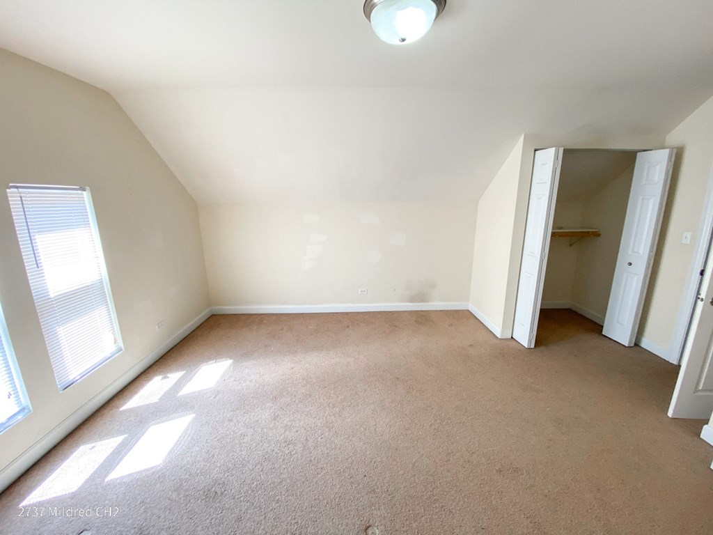 a bedroom with a carpeted floor and a closet in the background