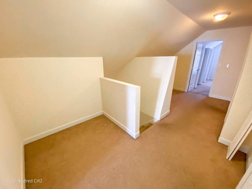 an empty room with white walls and a door at the end of the room