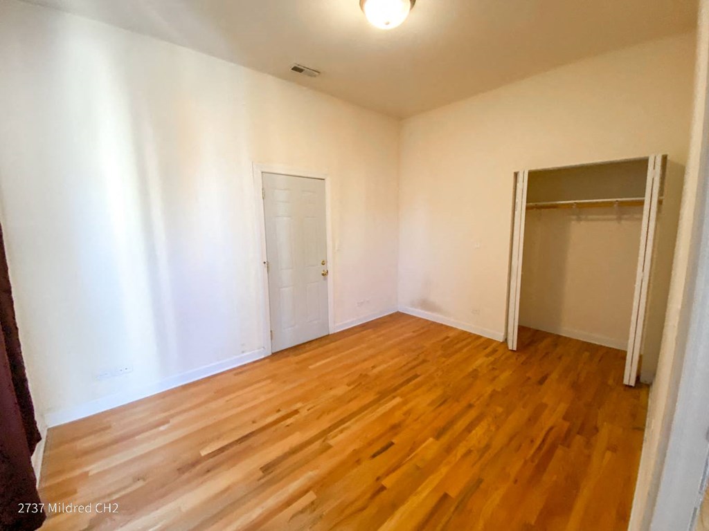 a bedroom with hardwood floors and white walls