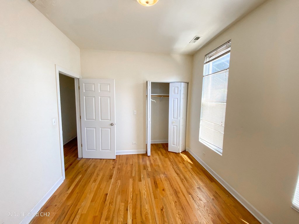 a bedroom with hardwood floors and white walls