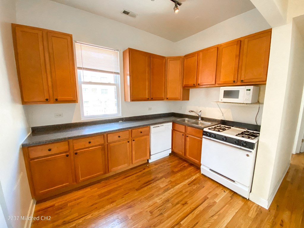 an empty kitchen with wood floors and wooden cabinets