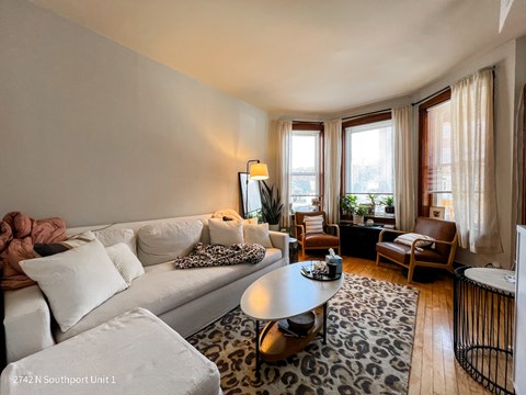 A living room with a white couch and a leopard print rug.