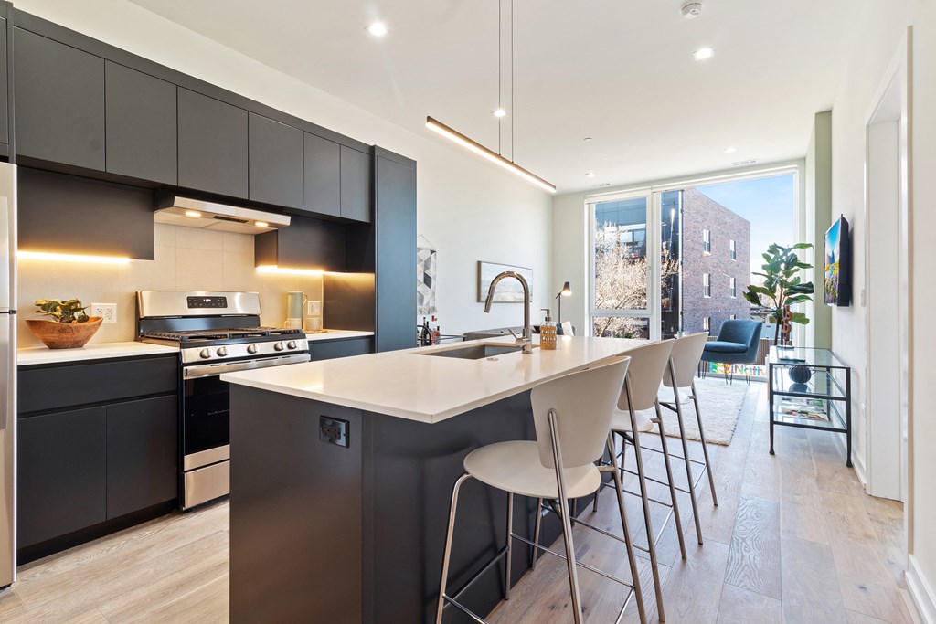 a kitchen with an island with bar stools and a large window