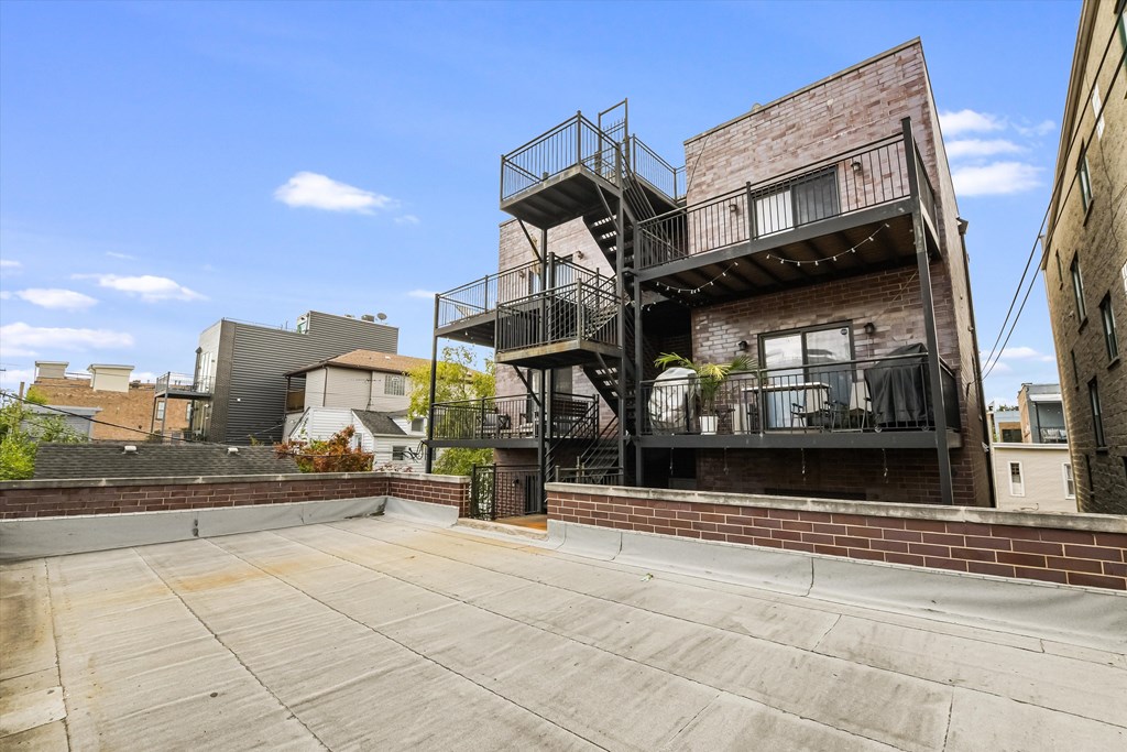 A large open patio area with a metal staircase leading to a balcony.
