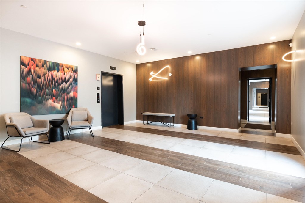 a lobby with chairs and a table with a large painting on the wall
