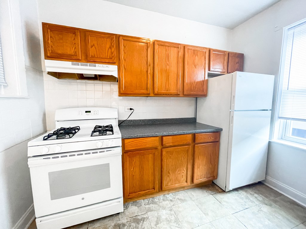 an empty kitchen with white appliances and wooden cabinets