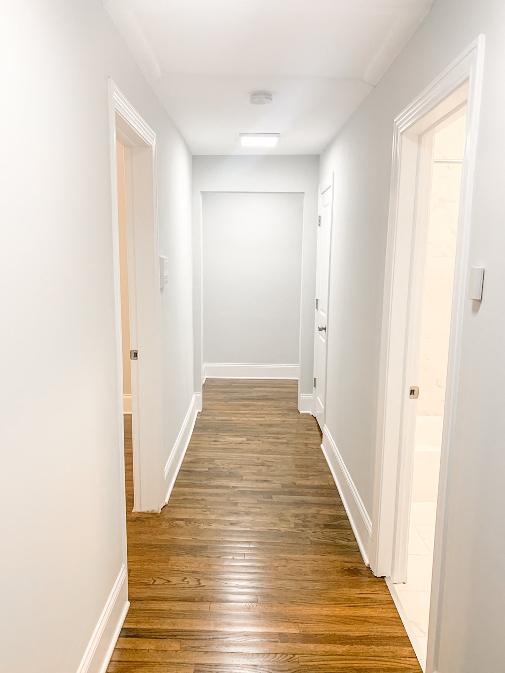 a hallway with wood floors and white walls and doors