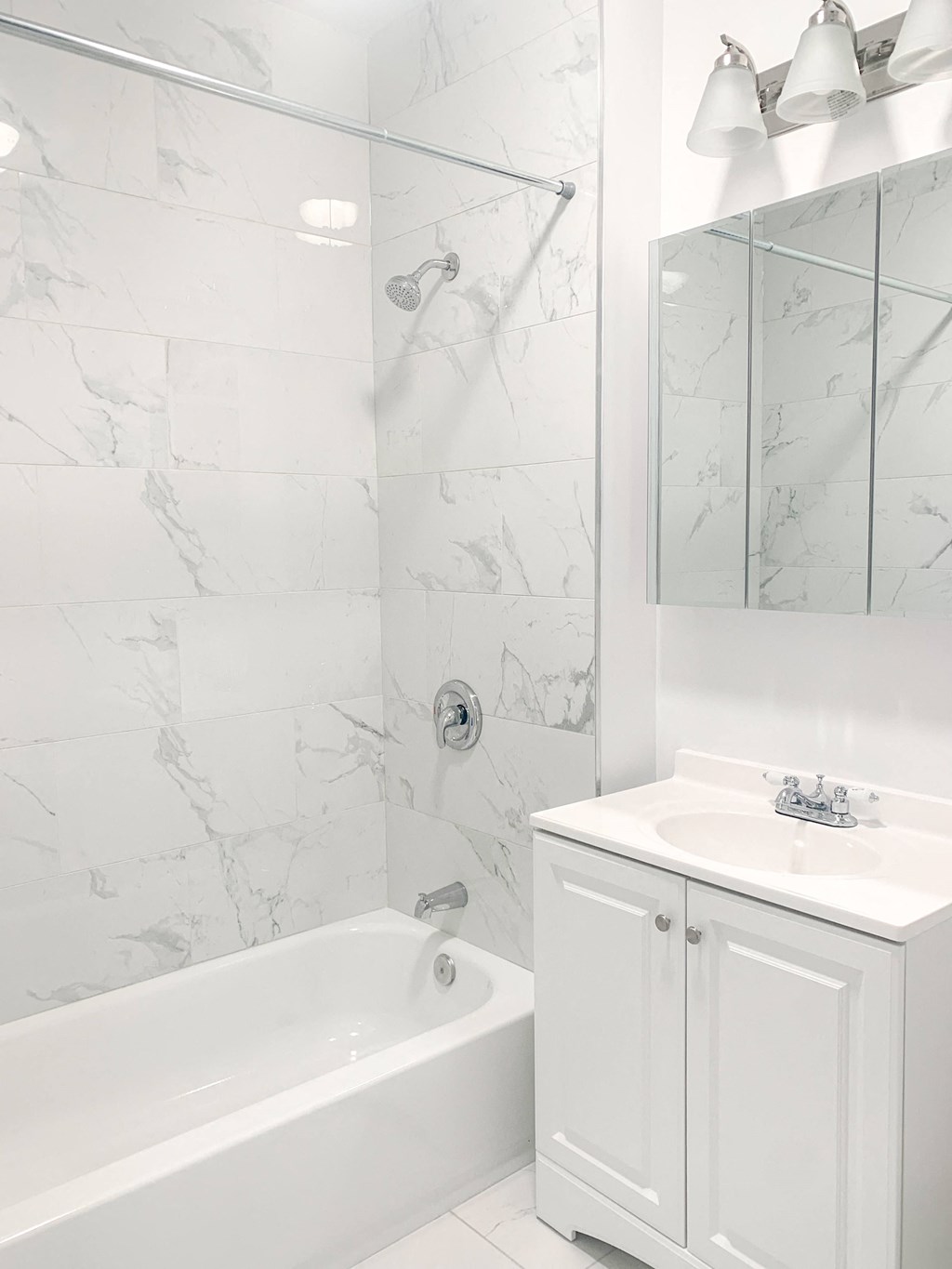 a white bathroom with a tub and a sink and a mirror