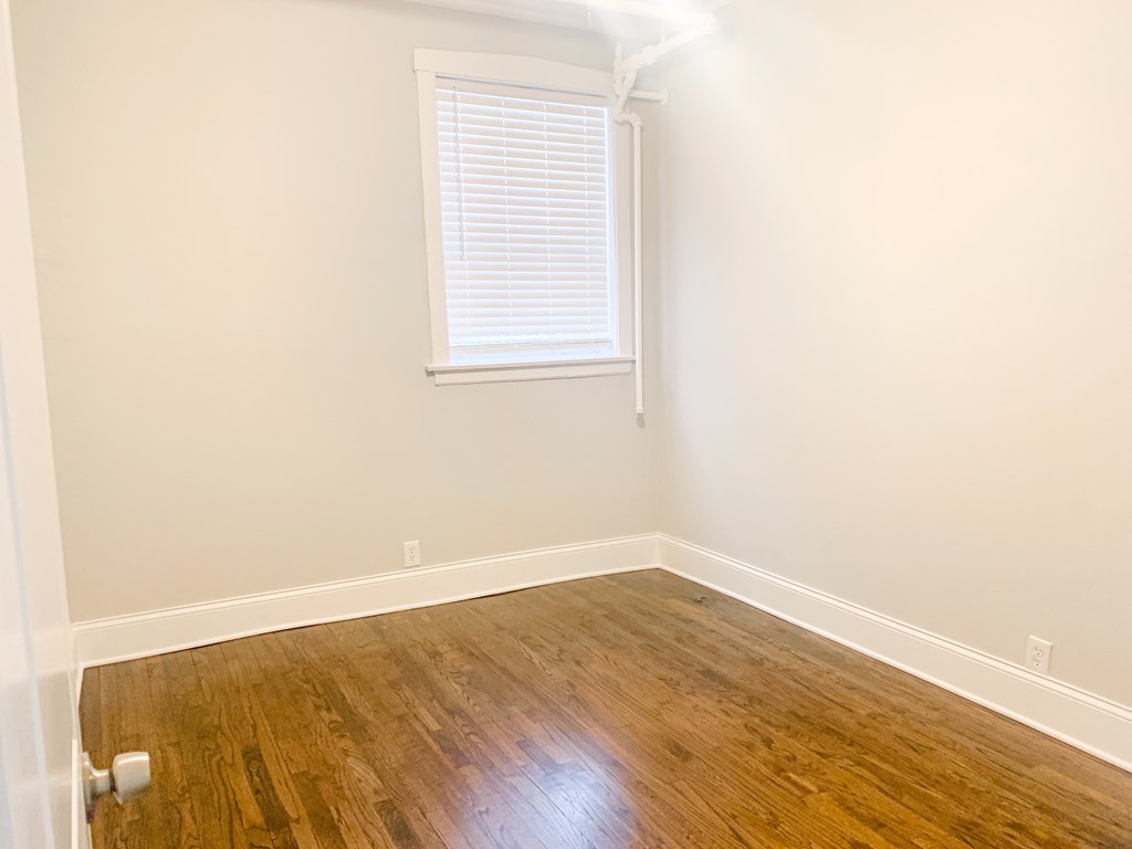 an empty room with wooden floors and a window