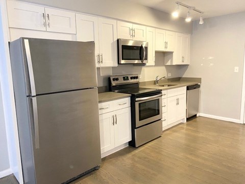 A kitchen with a stainless steel refrigerator, microwave, oven, and cabinets.