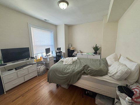 A bedroom with a bed, dresser, and a television.
