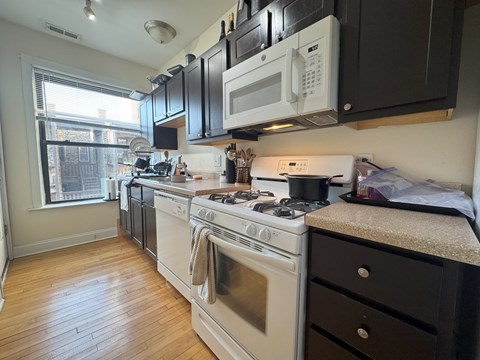 A kitchen with black cabinets and white appliances.
