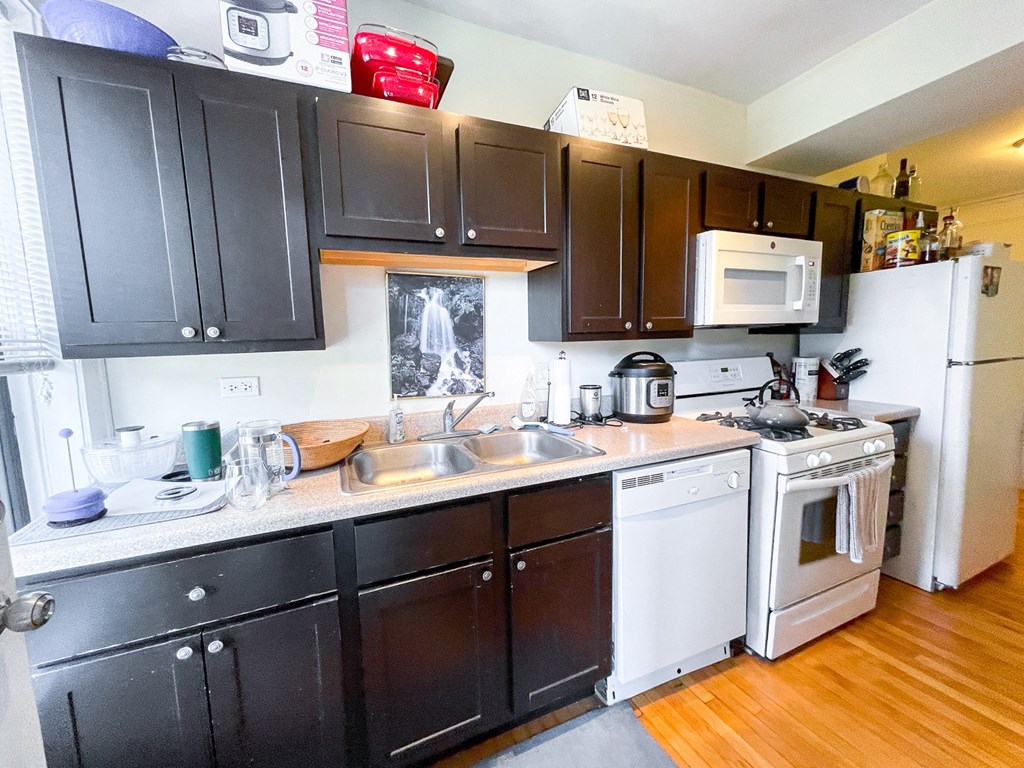 a kitchen with black cabinets and white appliances and a sink