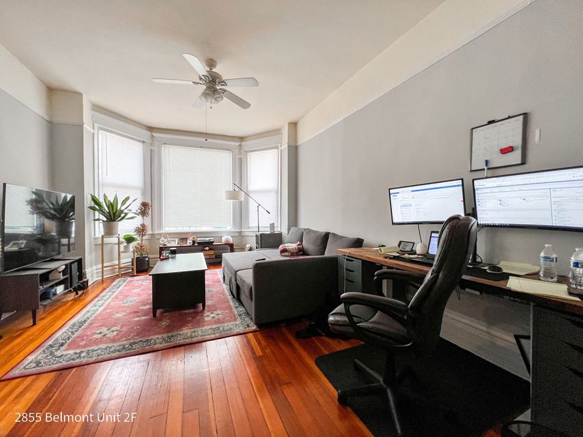 a living room with a couch and a desk with two computer monitors