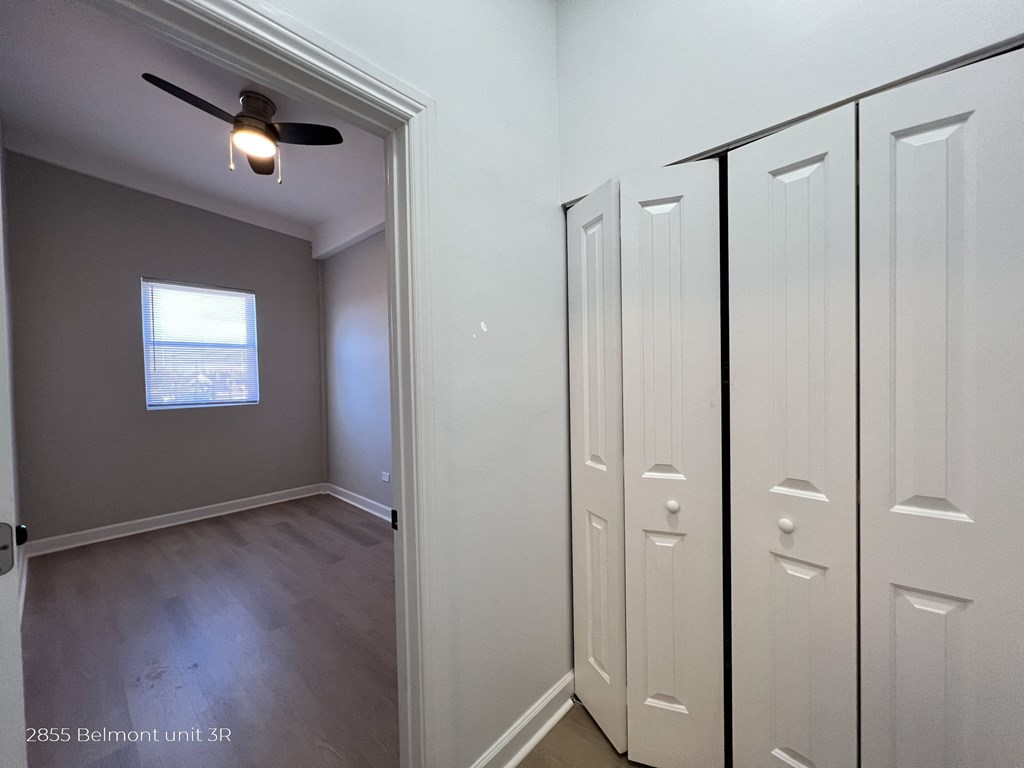 an empty bedroom with three closets and a ceiling fan