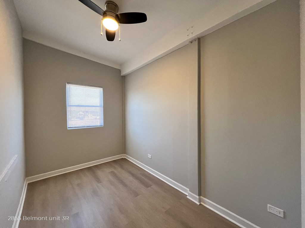 an empty room with a ceiling fan and a window