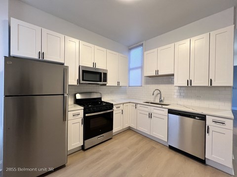 a kitchen with white cabinets and stainless steel appliances