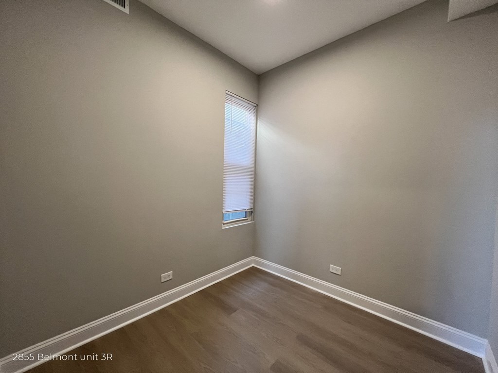 an empty room with wooden floors and a window