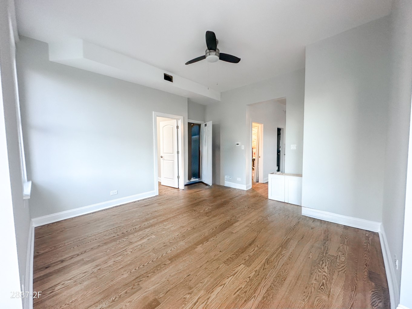 A room with wooden flooring and a ceiling fan.