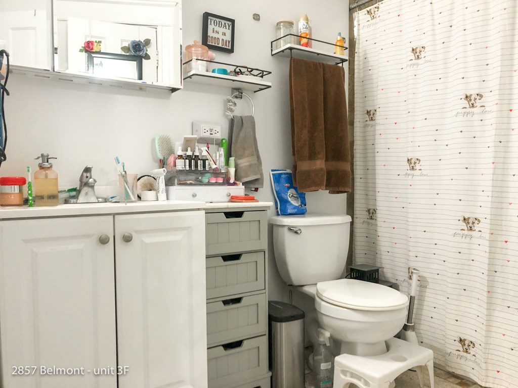 A small white bathroom with a toilet, sink, and a mirror.