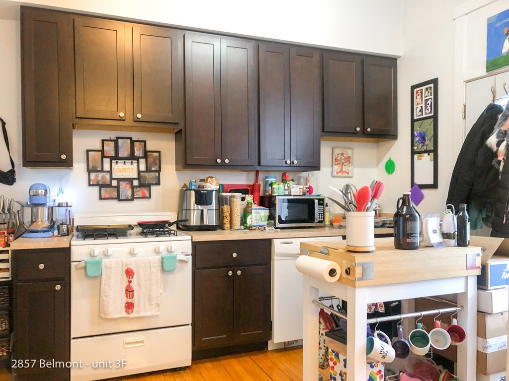 A kitchen with dark brown cabinets and a white stove top oven.